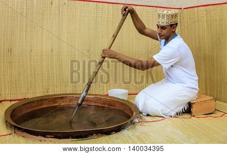 NIZWA, OMAN, MAY 27, 2016: factory worker stirs ingredients in a kettle in the process of making traditional Omani halwa