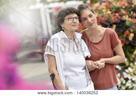 Home carer helping disabled woman walking with crutch