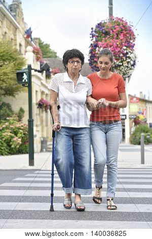 Home carer helping senior woman crossing the street 