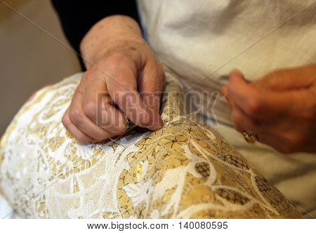 Hands Of The Elderly While Embroidering A Lace With Lace Pillow