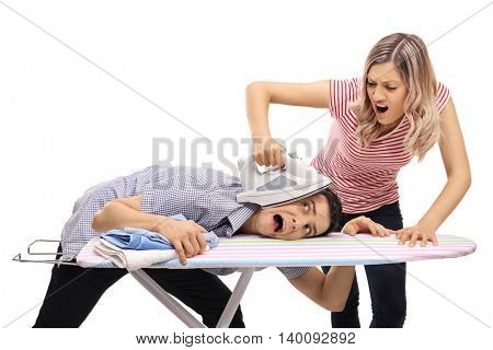 Angry young woman pressing the head of a man with an iron isolated on white background 