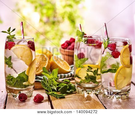 Wooden boards group of glasses with ice cubes alcohol cocktail number two hundred seventy seven raspberry cocktail mohito with straw and slide lime and mint leaf. Country life still. Light background.