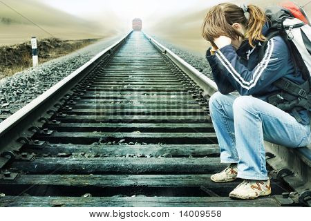 Jonge vrouw zittend op spoor met komende trein