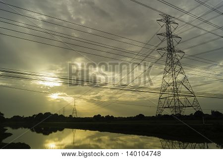 High voltage pylons on the rice field in the evening at sunset .