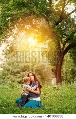 Full-body of happy family in city park at the sunset. Mother and son.