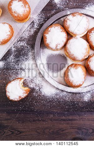 German donuts - berliner with jam and icing sugar in a tray on a dark wooden background. Top view with copyspace