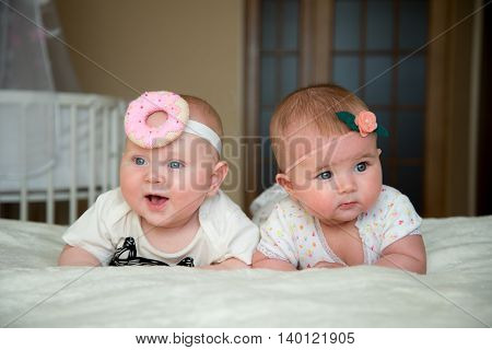 twin baby boy and girl lie on the bed and smile