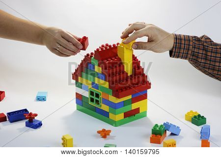 Toy house built by family - husband and wife. Their hands have rings. The symbol of building relationships