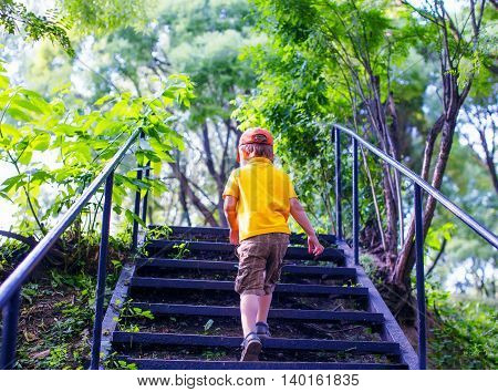 toddler climbs the stairs in the park. concept of growing up. step by step the child rises higher and goes farther