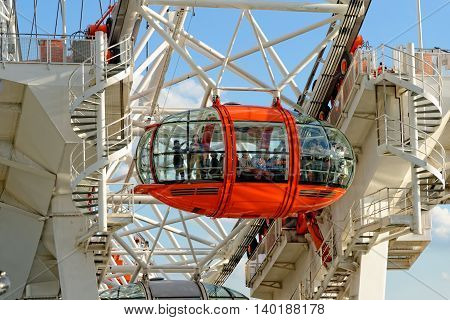 LONDON UK - JULY 1 2014: Tourists enjoy the view over the city in the capsules of the London Eye Europe's tallest Ferris wheel on the South Bank of the River Thames a famous tourist attraction.