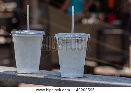 Two cold carbonated drinks in transparent plastic cups