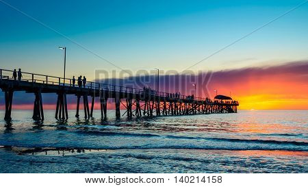 People relaxing on the Henley Beach Jetty at sunset South Australia. Color-toning effect applied