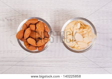 Almond nuts and sliced shavings in small glass dishes on a wooden table