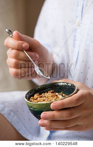 Young woman with muesli bowl. Girl eating breakfast cereals with nuts pumpkin seeds oats and yogurt in bowl. Girl holding homemade granola. Healthy snack or breakfst in the morning.
