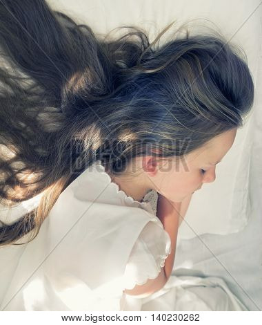 little girl is sleeping and her long hair spreads on pillow
