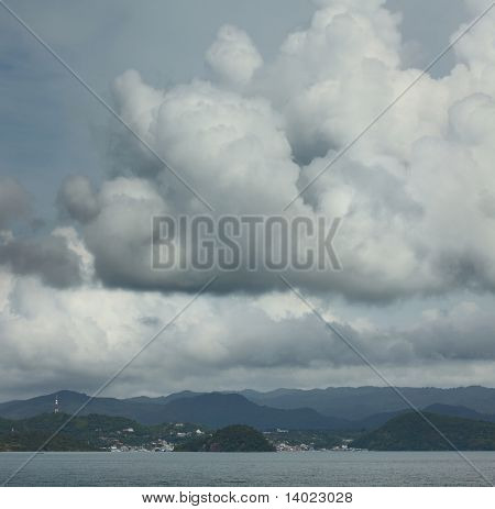 Fluffy clouds over city located in mountains. Labuan Bajo. Indonesia