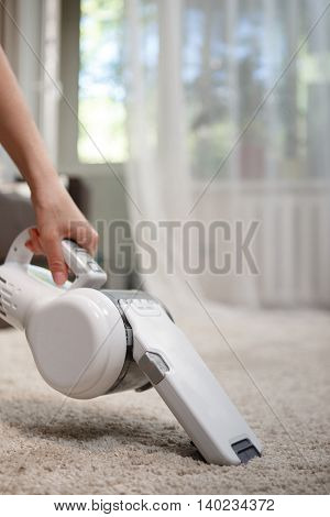 Woman cleaning carpet cordless handheld vacuum cleaner