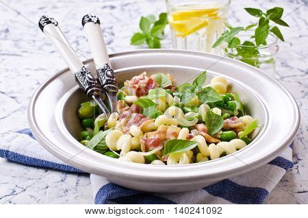 Pasta with bacon and vegetables in portion plate. Selective focus.
