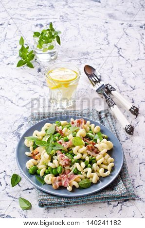 Pasta with bacon and vegetables in portion plate. Selective focus.