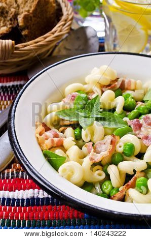 Pasta with bacon and vegetables in portion plate. Selective focus.