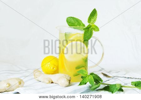 Lemonade with ginger and mint in kitchen. Home made ginger lemonade on striped napkin or towel. Healthy drink lemonade.