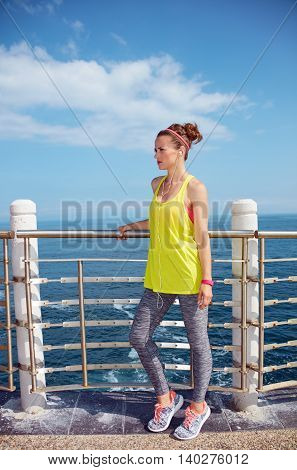Young Woman In Fitness Outfit Looking Aside At Embankment