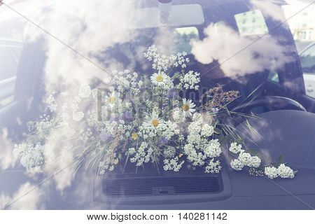 bouquet of field flower behind a windshield in a car