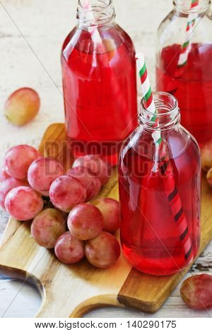 Fresh grape juice in a glass bottle and ripe berries on the table. Rustic style. Health and diet food. Selective focus