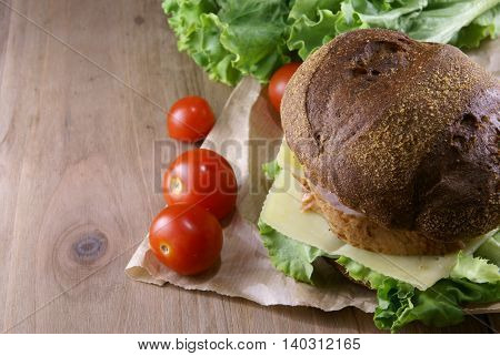 Picnic, sandwich with meat, cheese and fresh vegetables is lying on a rustic wooden table.
