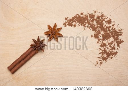Magic wand made of cinnamon stick, star anise and cocoa powder on wooden background. Magic aromatic spices for healthy and flavored food.