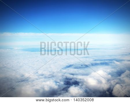 Blue sky with white cumulus clouds, view ourside an airplane. Cloudscape in the sun, good weather with copy space. Nature background with clear blue sky and fluffy clouds.