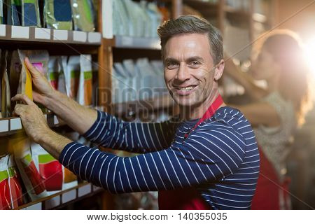 Portrait of male staff arranging grocery items on shelf in supermarket