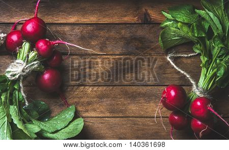 Fresh radish bunches over rustic wooden background, top view, copy space, horizontal composition