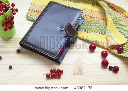 Summer planning - diary on a table with different mix berries wooden background.