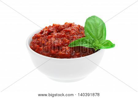 Red adjika sauce with basil leafs isolated