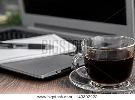 A cup of coffee with laptop on background