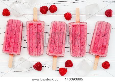 Homemade vegan raspberry coconut milk popsicles - ice pops - paletas with chia seeds on rustic white wooden background
