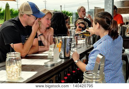 Middletown Rhode Island - July 18 2015: Bar tender pouring a bottle of white wine for a young couple to taste at the Newport Winery Vineyard