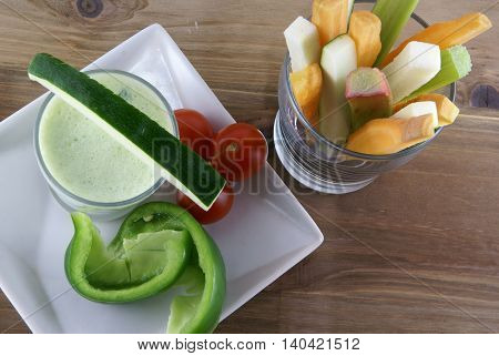 Useful summer snack: vegetables and yogurt sauce with herbs. Against the background of a rustic wooden table