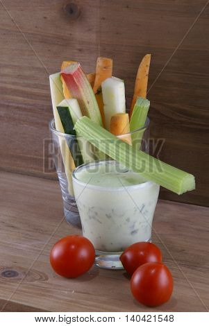 Useful summer snack: vegetables and yogurt sauce with herbs. Against the background of a rustic wooden table