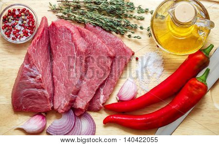Raw meat vegetables and spices . Fresh beef peppers red onion garlic thyme olive oil. The ingredients for a tasty lunch