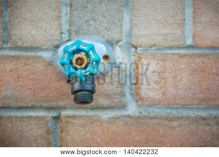 tap water spigot on brick wall, aqua blue green valve