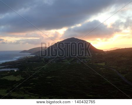 Sunset over Kokohead Crater through the clouds highway runs along the coastline of Oahu Hawaii. December 2015.