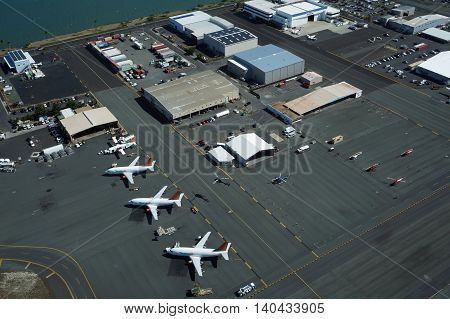 HONOLULU - APRIL 18: Aerial view of planes helicopters and cars parked by buildings at the Honolulu International Airport HNL next to the water on Oahu Hawaii. April 18 2016.