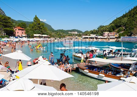 CORFU-AUGUST 26: Palaiokastritsa beach with crowd of people sunbathing on the beach August 262014 on Corfu Greece. Palaiokastritsa is a village with famous beaches in the North West of Corfu.