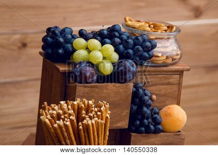 fresh fruits and berries plums, grapes on a wooden stand and crispy breadsticks in glass jars standing on the wedding Welkom
