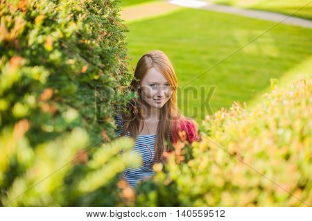 A girl looks out of bushes near the castle in the Czech Republic