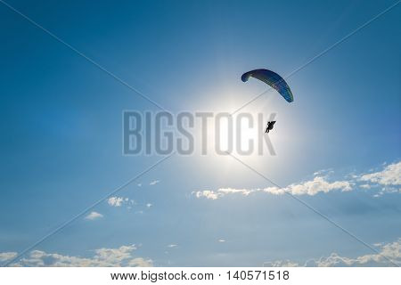 Paragliding in the sky. Man flying a paraglider on the sun.