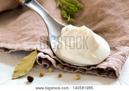 Mayonaisse in a spoon on a rustic napkin with spices
