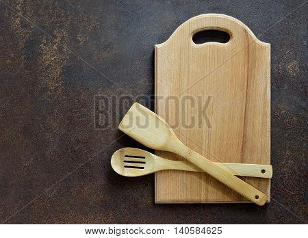Wooden kitchen utensils on a dark surface overhead view